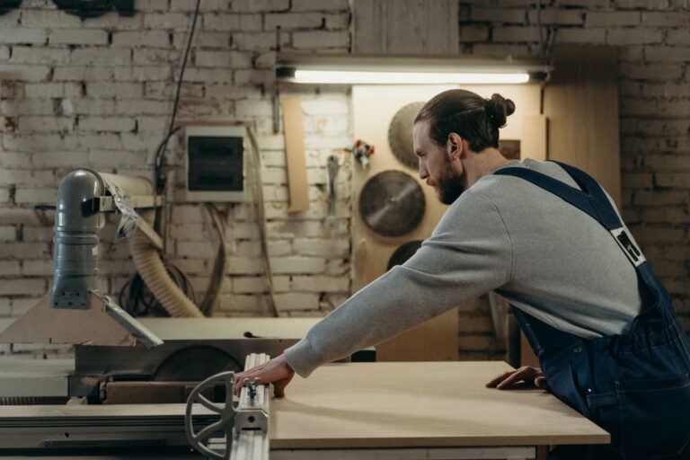 Meubelmaker zaagt een plaat op de formaatzaag in zijn werkplaats